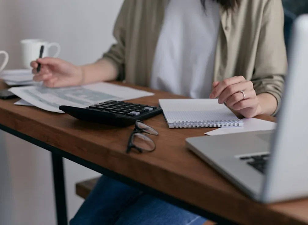 A person sitting at a desk with a calculator