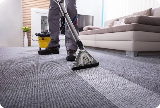 A man operates a vacuum cleaner on a carpet
