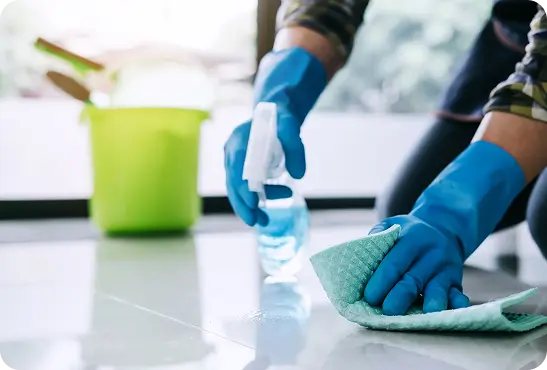 A person scrubbing a floor with a sponge and cleaning cloth
